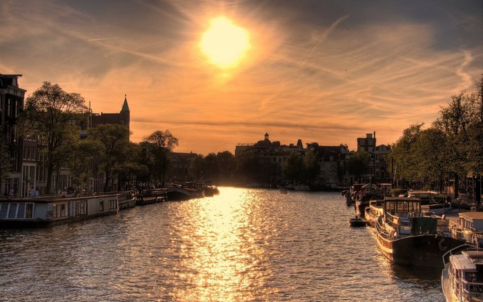 Sunset over Amsterdam canal with boats