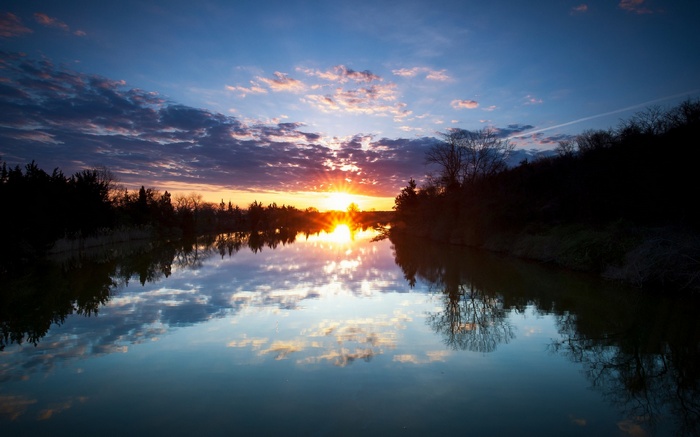 Sunset over a calm river with reflections