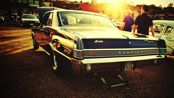 Pontiac GTO parked at sunset with people