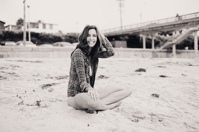 Woman in plaid shirt sitting on sand at beach
