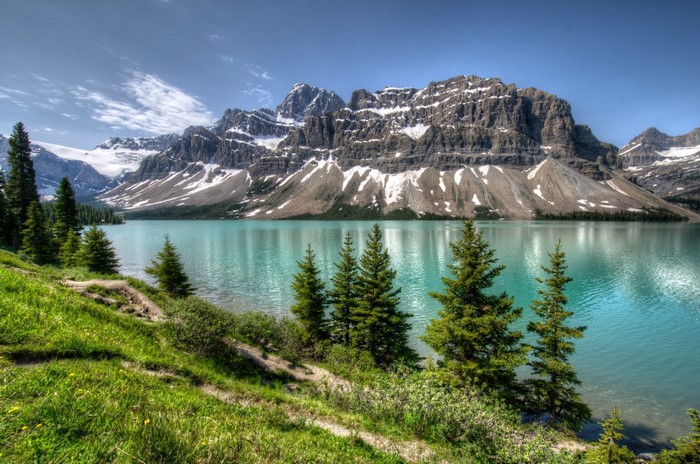 Turquoise lake with snow-capped mountains and pine trees