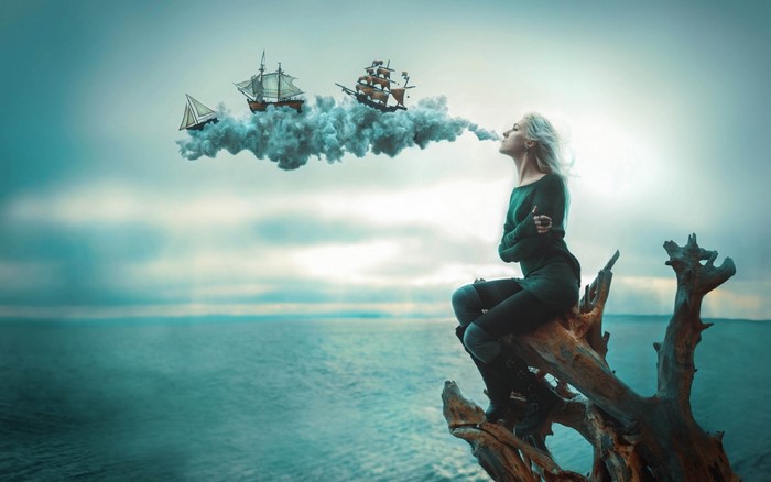 Woman exhaling smoke with ships on clouds over ocean