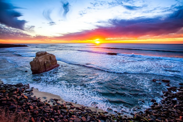 Sunset over the ocean with a large rock formation