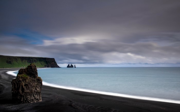 Black sand beach with sea stacks and cliffs