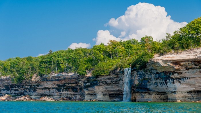 Serene Caribbean Cliffside with Waterfall and Turquoise Bay