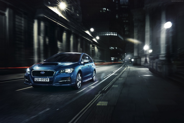 Blue Subaru Levorg driving through a city at night