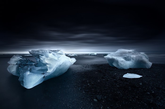 Icebergs on a dark beach with moody sky
