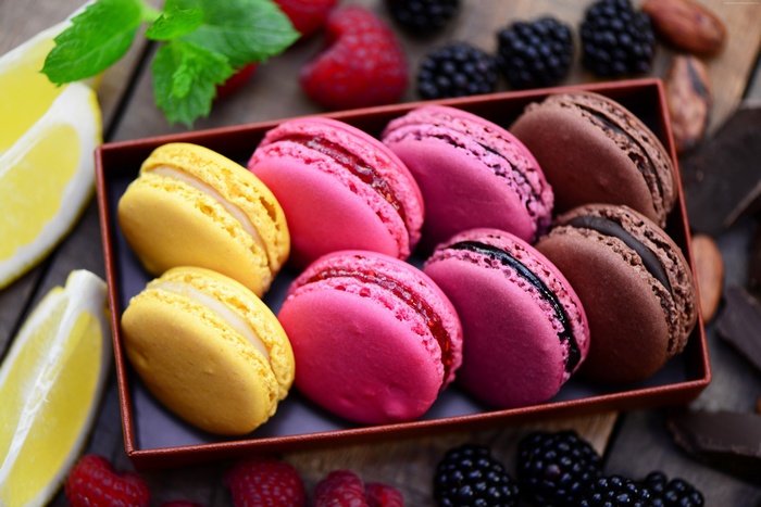 Assortment of colorful macarons with berries and lemon slices