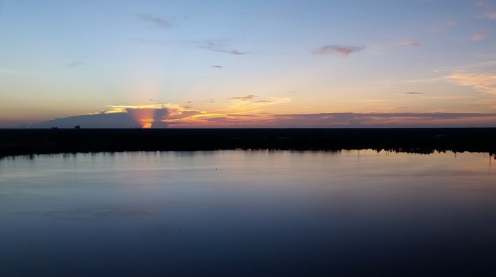 Sunset over a calm lake with sun rays through clouds