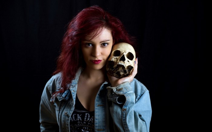 Woman with red hair holding a skull
