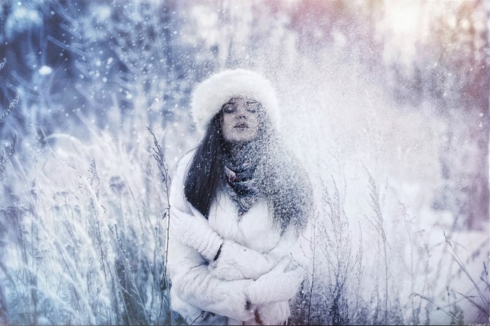 Woman in white fur coat and hat in snow