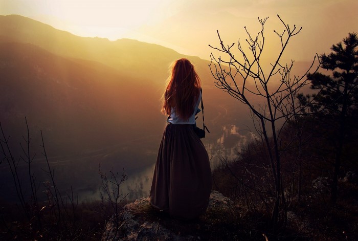 Woman with red hair on a mountain at sunset