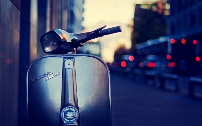 Vintage Vespa scooter on a city street at dusk