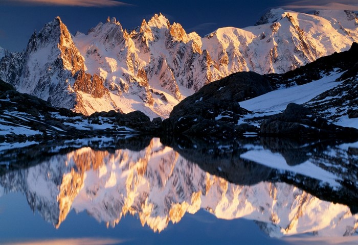 Snowy mountain range reflected in a lake at sunrise