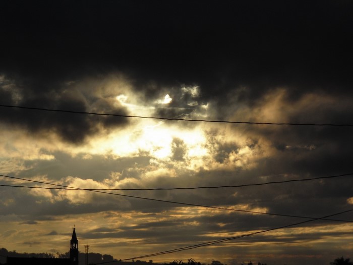 Sunlight breaking through dark clouds over a cityscape