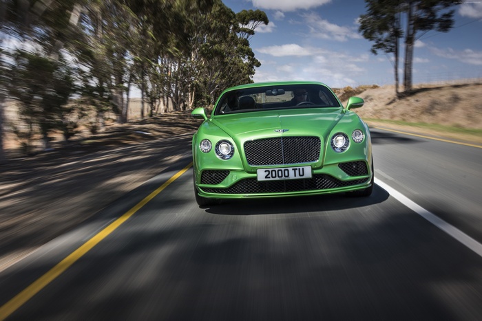 Green Bentley Continental GT Speed driving on a road