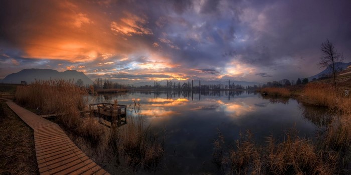 Sunset over a lake with reeds and mountains