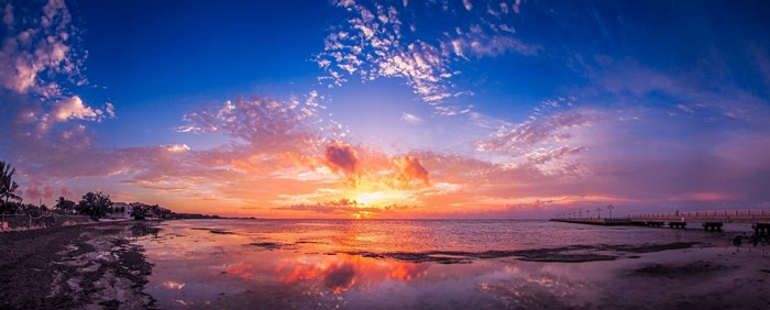 Panoramic sunset over the sea with a pier