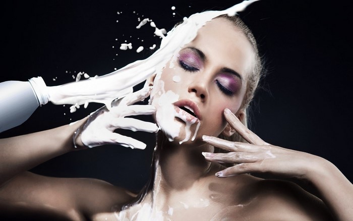 Woman with milk pouring on her face and hands