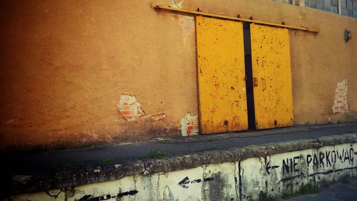 Yellow sliding doors on a textured wall with graffiti