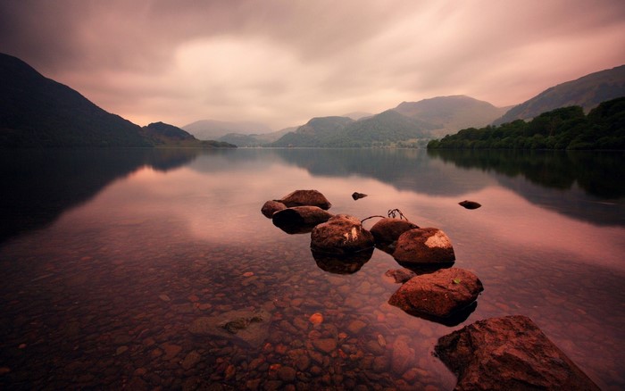 Lake and mountains at sunset with rocks in the foreground