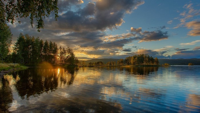 Sunset over a calm lake with trees and clouds