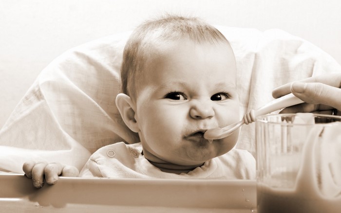 Baby being fed with a spoon in a high chair