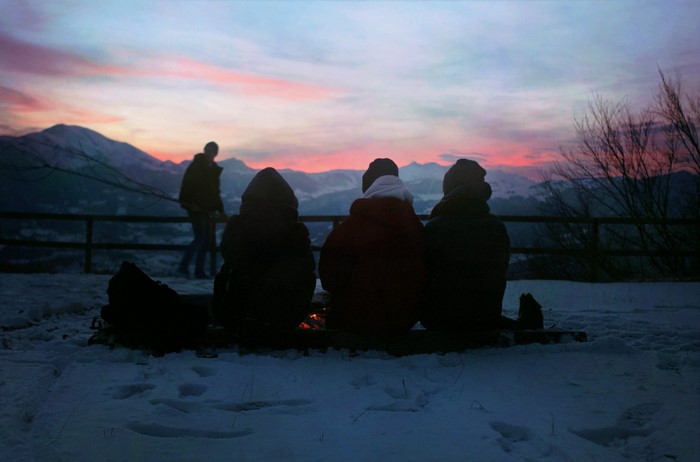 People watching sunset over snowy mountains