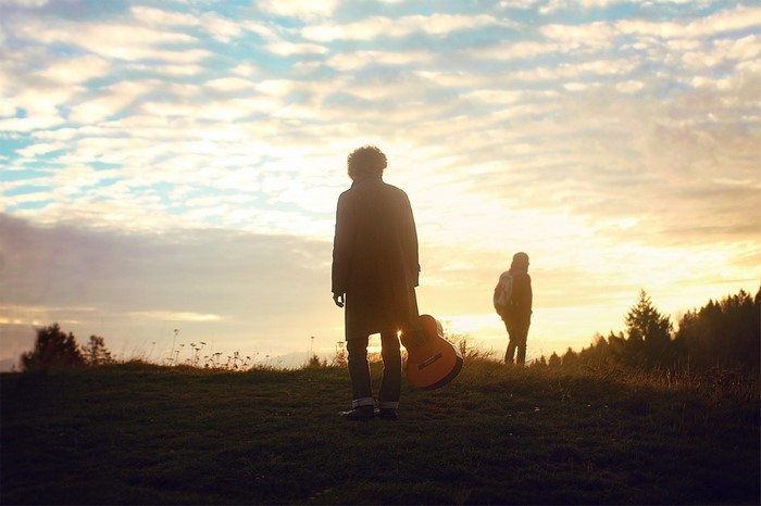 Two people with a guitar at sunset