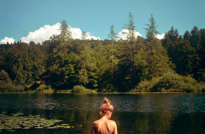 Woman in lake with forest and cabin background