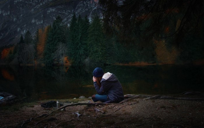 Woman sitting by a lake in a forest