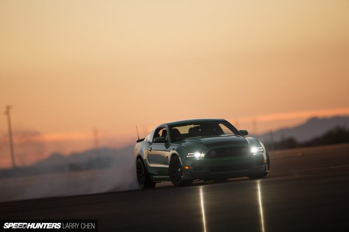 Green Ford Mustang drifting at sunset