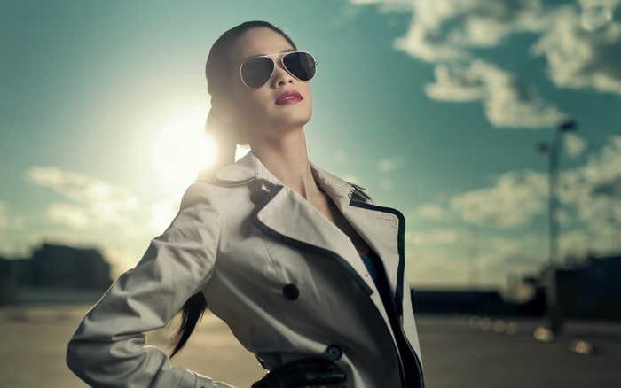 Woman in sunglasses and trench coat against the sun
