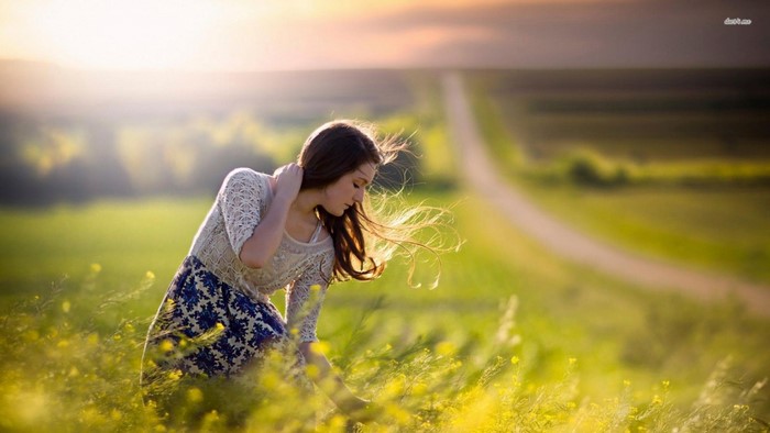 Woman in a field of yellow flowers at sunrise