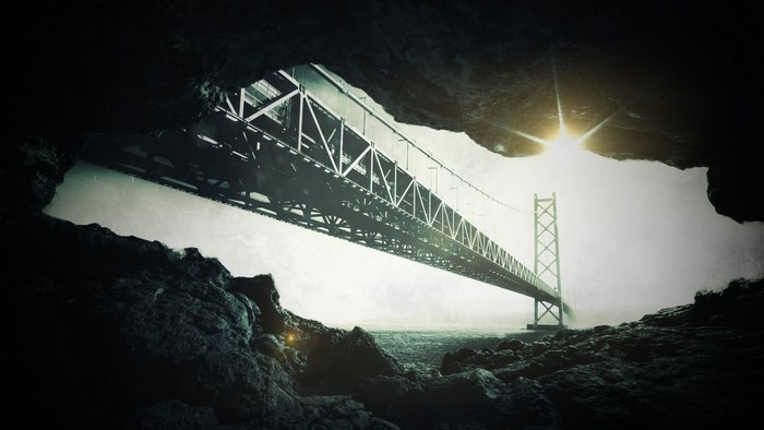 Bridge over water seen from a cave entrance