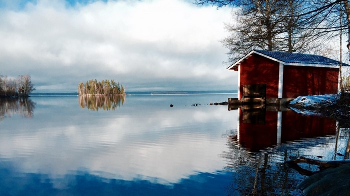 Red boathouse on a calm lake in winter