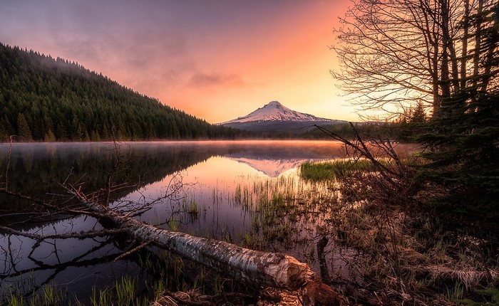 Mountain reflection at sunrise over misty lake