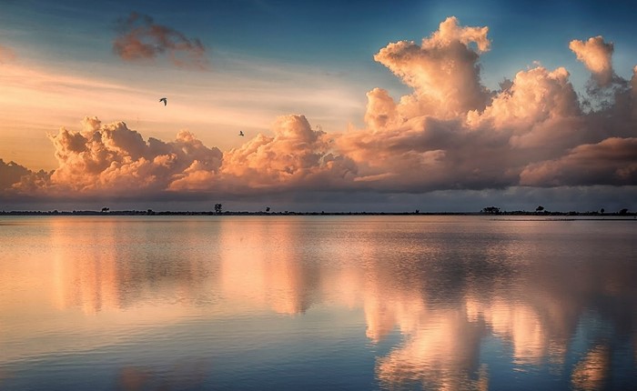 Sunset over a calm lake with birds flying