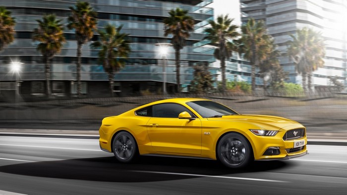 Yellow Ford Mustang driving on a city street