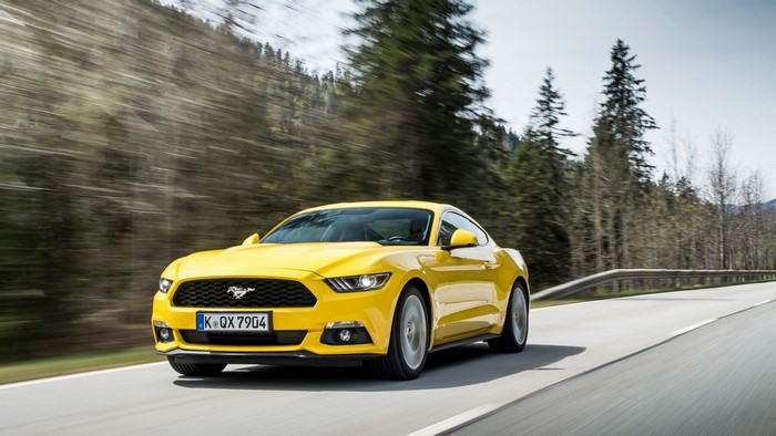 Yellow Ford Mustang driving on a road