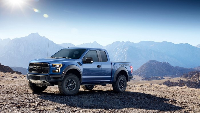 Blue Ford F-150 Raptor pickup truck in mountains