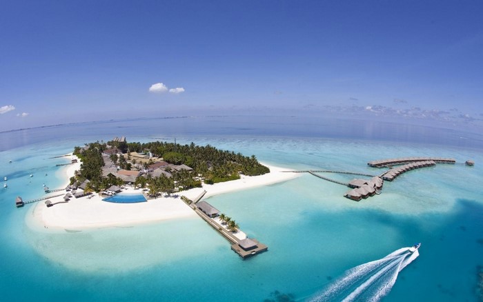 Aerial view of a tropical island resort with overwater bungalows