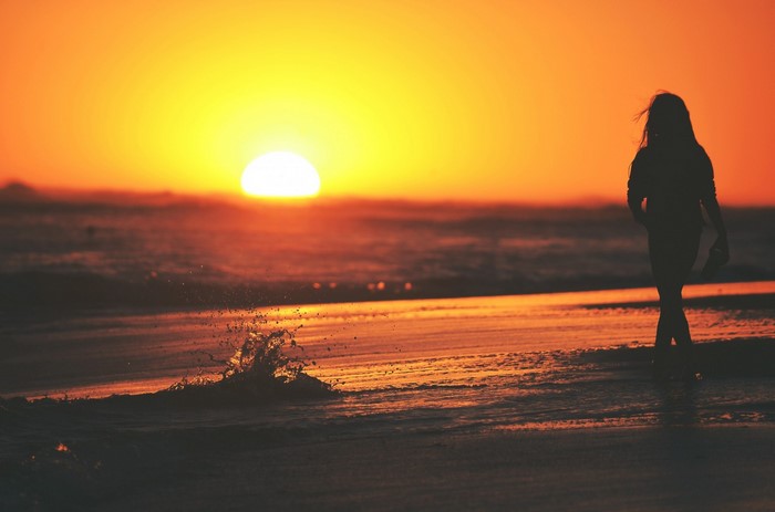 Woman walking on beach at sunset