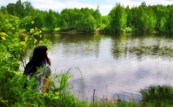 Woman sitting by a lake in a forest