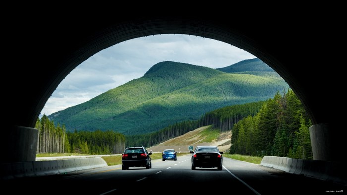 Cars driving out of a tunnel towards mountains