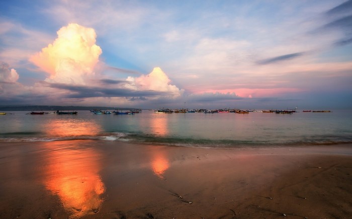 Boats on the sea at sunset with colorful clouds and reflection