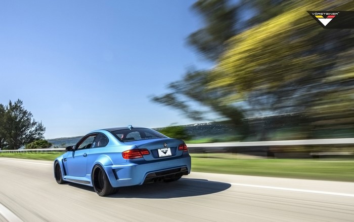 Blue BMW M3 GTRS3 by Vorsteiner driving on a road