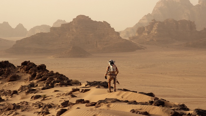 Astronaut on a rocky, sandy planet with mountains