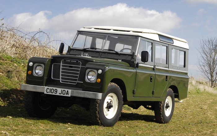 Green Land Rover Series III parked on a grassy hill