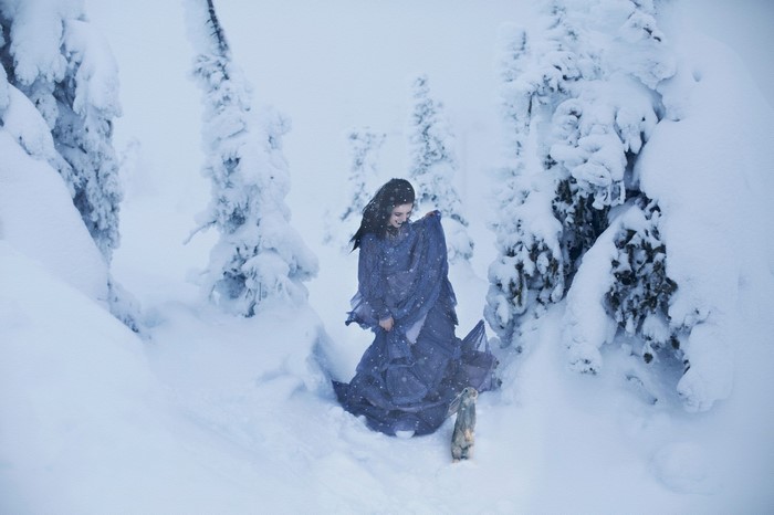 Woman in blue dress with rabbit in snowy forest